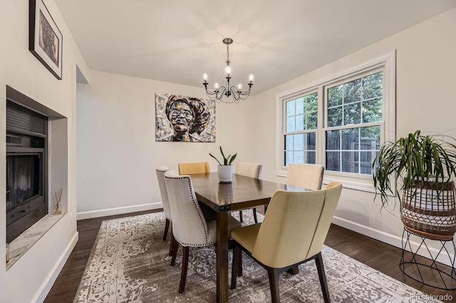dining area with a chandelier, dark wood-type flooring, and baseboards