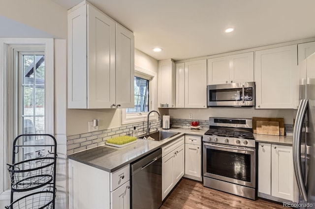 kitchen with appliances with stainless steel finishes, a sink, white cabinetry, dark wood-style floors, and recessed lighting