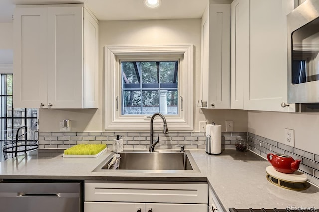 kitchen featuring stainless steel appliances, a sink, decorative backsplash, and white cabinets