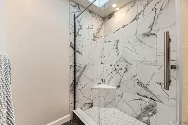 full bathroom with a marble finish shower and baseboards