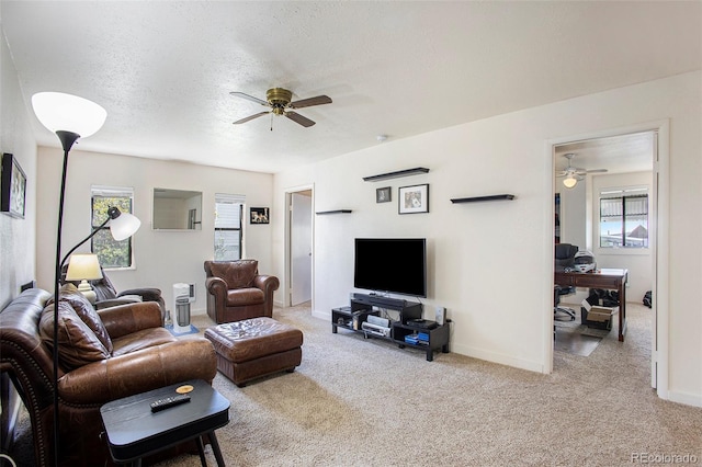 carpeted living room featuring ceiling fan and a textured ceiling