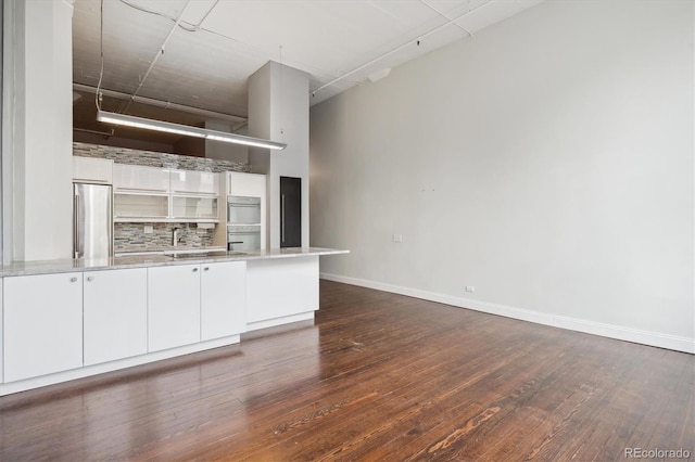 720 16th St Unit 306, Denver, CO 80202 - kitchen with stainless steel fridge, dark wood-style flooring, backsplash, and white cabinetry