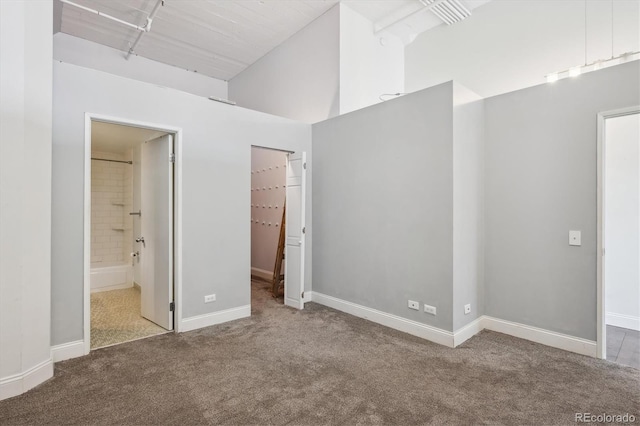 720 16th St Unit 306, Denver, CO 80202 - unfurnished bedroom featuring carpet floors, a high ceiling, a spacious closet, baseboards, and connected bathroom