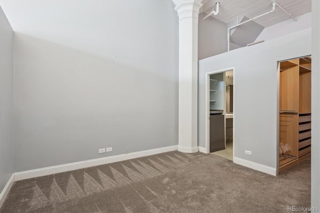 720 16th St Unit 306, Denver, CO 80202 - unfurnished bedroom featuring a spacious closet, carpet, ornate columns, baseboards, and high vaulted ceiling
