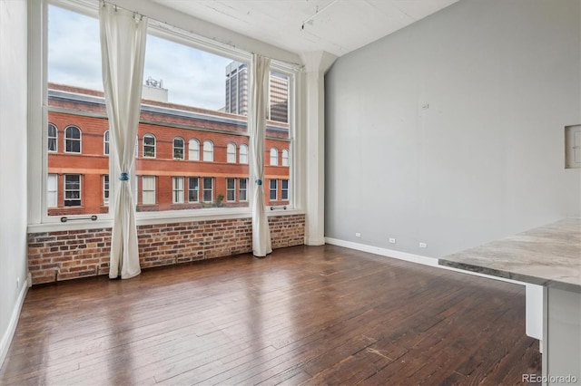 720 16th St Unit 306, Denver, CO 80202 - spare room featuring dark wood-type flooring, baseboards, and brick wall