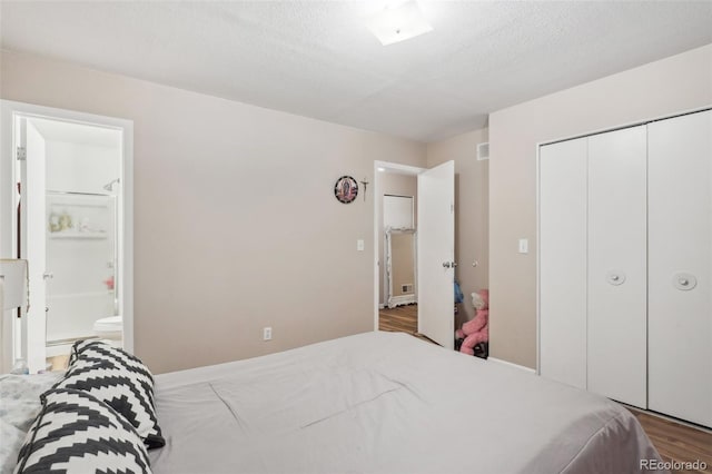 bedroom featuring wood-type flooring, a textured ceiling, and ensuite bathroom