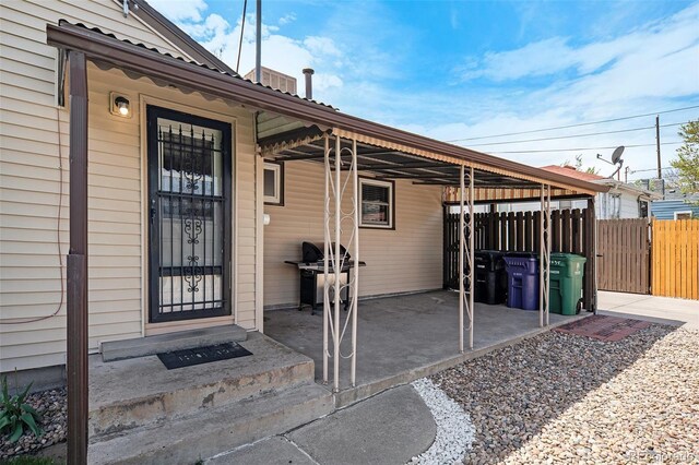 view of exterior entry with fence and metal roof