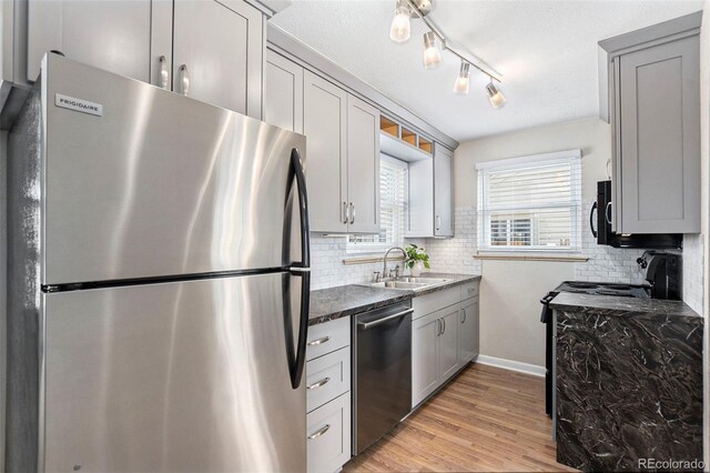 kitchen featuring black appliances, a sink, tasteful backsplash, and light wood finished floors