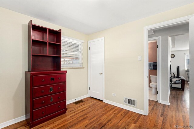 unfurnished bedroom with multiple windows, wood finished floors, and baseboards