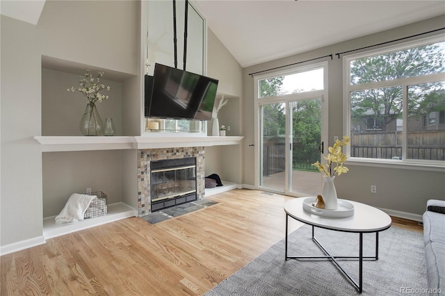 8652 Aberdeen Cir, Highlands Ranch, CO 80130 - living area featuring wood finished floors, a fireplace with flush hearth, lofted ceiling, and baseboards