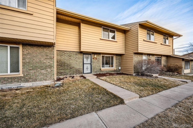 townhome / multi-family property featuring brick siding and a front yard