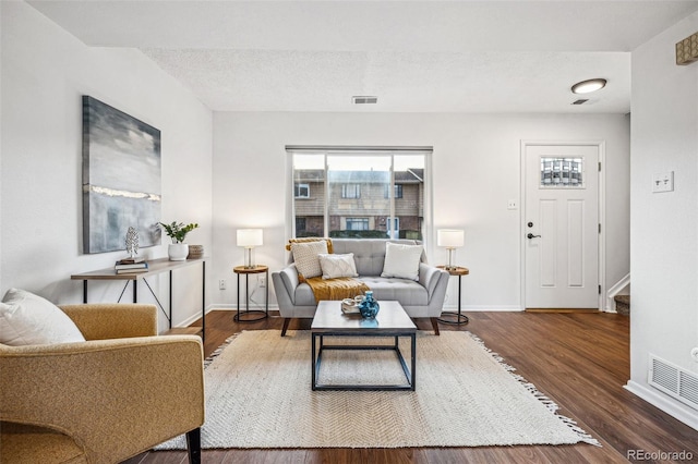 living room with visible vents, baseboards, and wood finished floors