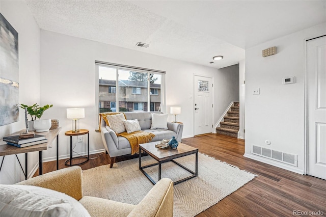 living area featuring stairway, wood finished floors, and visible vents