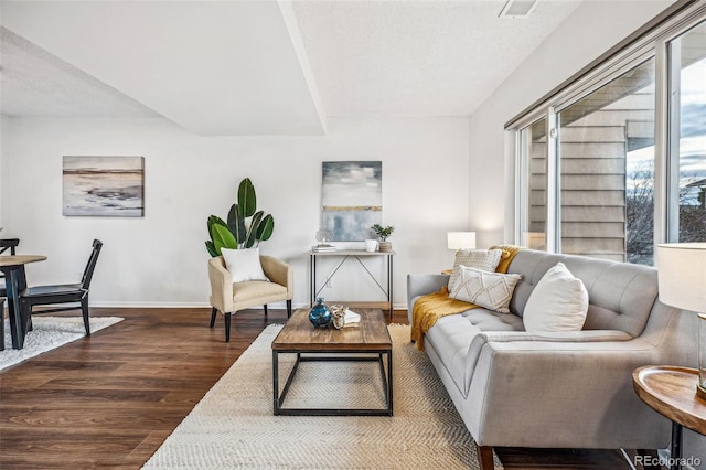 living area with a textured ceiling, baseboards, and wood finished floors