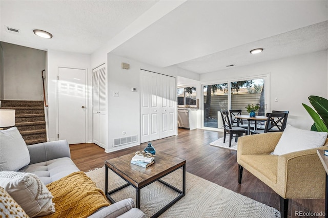 living room featuring visible vents, stairway, baseboards, and wood finished floors