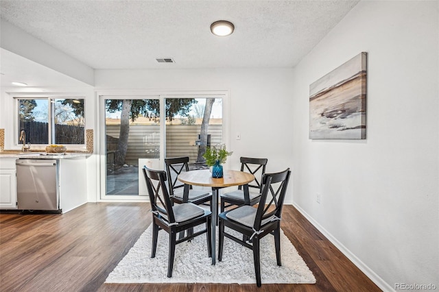 dining area featuring dark wood finished floors, visible vents, and a healthy amount of sunlight