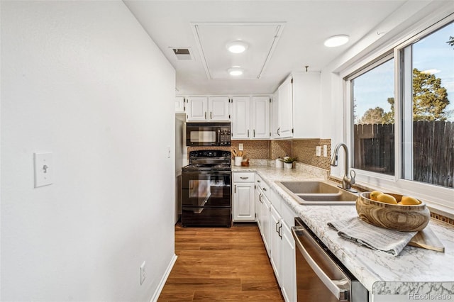 kitchen with wood finished floors, a sink, visible vents, black appliances, and tasteful backsplash