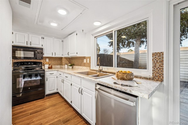 kitchen featuring a sink, white cabinetry, light wood-style floors, black appliances, and tasteful backsplash