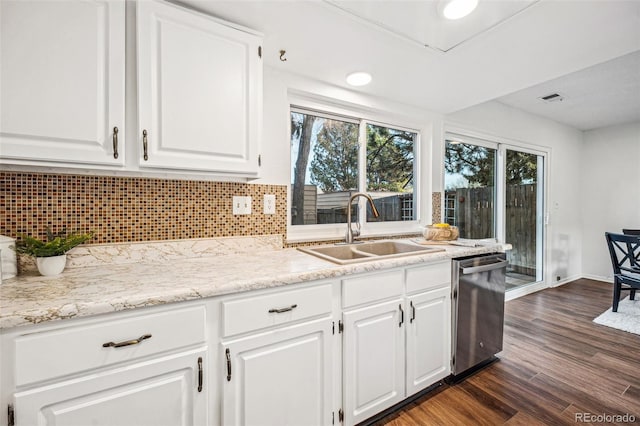 kitchen with white cabinets, backsplash, dark wood-style flooring, stainless steel dishwasher, and a sink