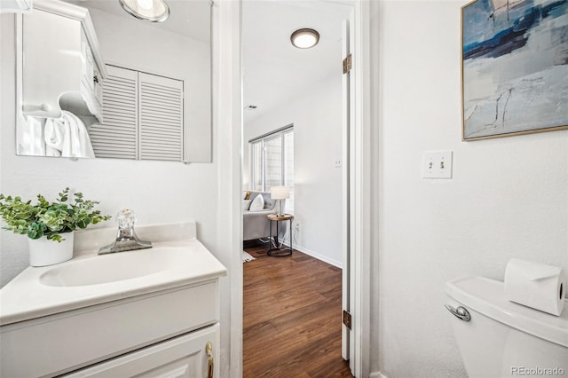 bathroom featuring baseboards, vanity, toilet, and wood finished floors