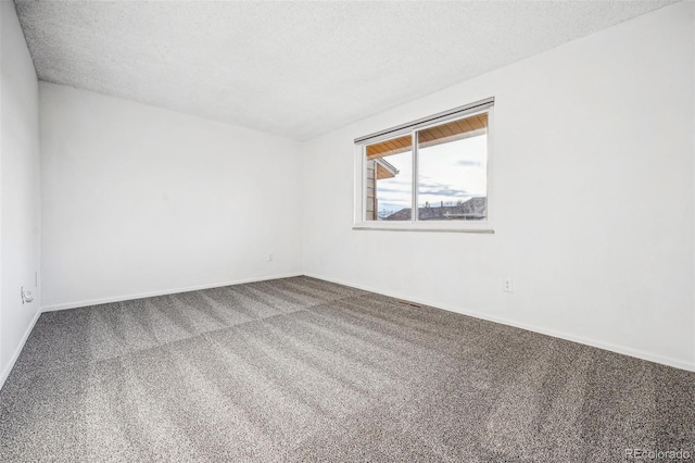 spare room featuring a textured ceiling, carpet floors, and baseboards