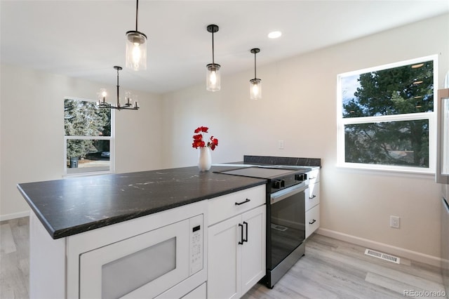 kitchen featuring built in microwave, pendant lighting, white cabinets, a chandelier, and stainless steel range with electric cooktop