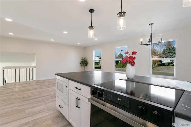 kitchen featuring white microwave, light hardwood / wood-style flooring, stainless steel electric range oven, decorative light fixtures, and white cabinetry