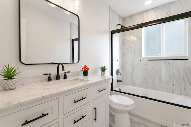 full bathroom with combined bath / shower with glass door, hardwood / wood-style floors, vanity, and toilet