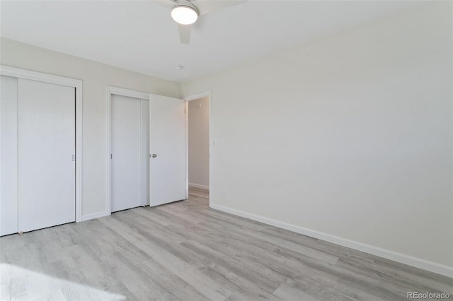 unfurnished bedroom featuring ceiling fan, light wood-type flooring, and two closets