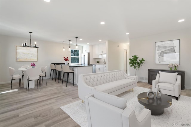 living room featuring light hardwood / wood-style floors, sink, and an inviting chandelier