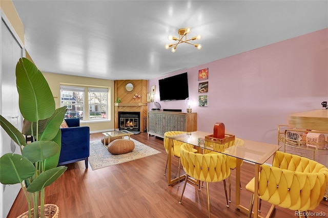 dining space with an inviting chandelier, a glass covered fireplace, and wood finished floors