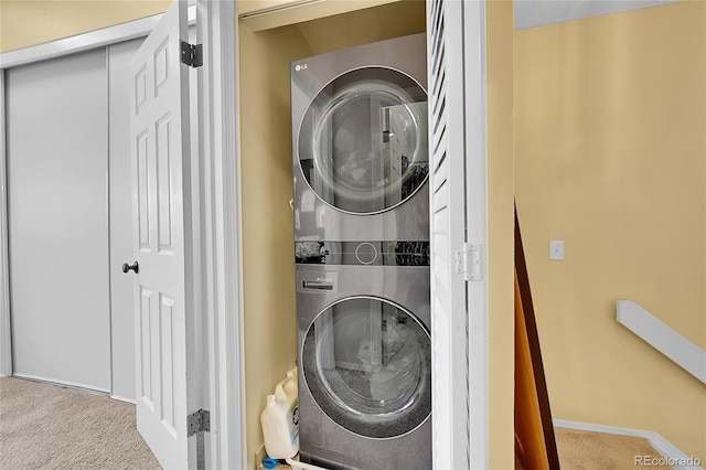 laundry room featuring carpet flooring, stacked washer and dryer, laundry area, and baseboards