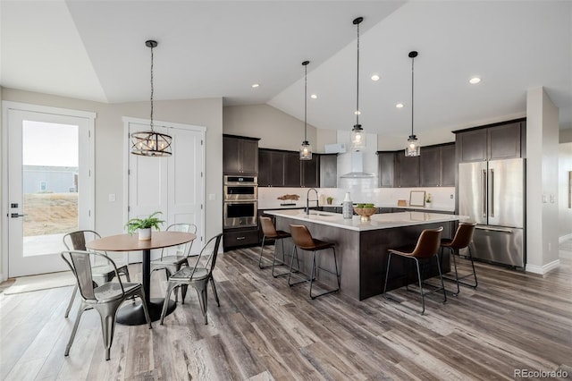 kitchen with a large island, dark brown cabinetry, stainless steel appliances, and decorative light fixtures