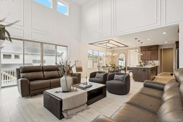living room with a chandelier, a high ceiling, and light wood-style flooring