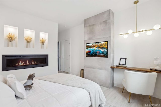 bedroom featuring wood finished floors and a lit fireplace