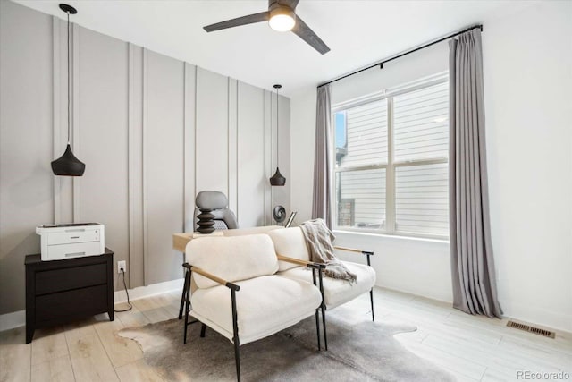 sitting room with ceiling fan and light wood-type flooring