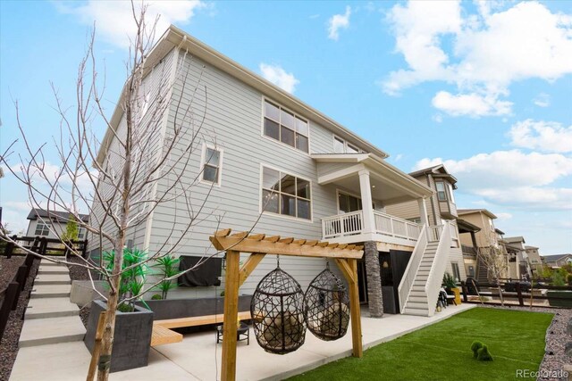 back of house with stairway, a patio area, and a lawn