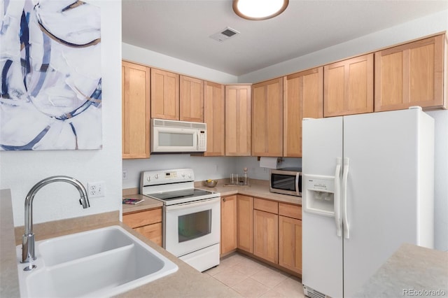 kitchen with light tile patterned flooring, white appliances, sink, and light brown cabinets