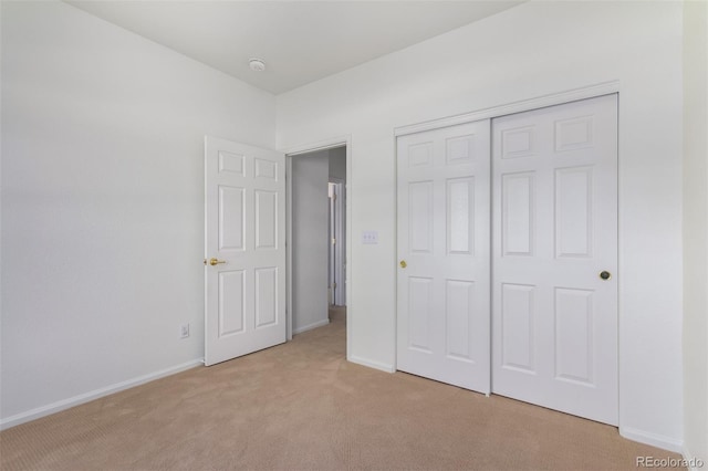 unfurnished bedroom featuring light carpet and a closet