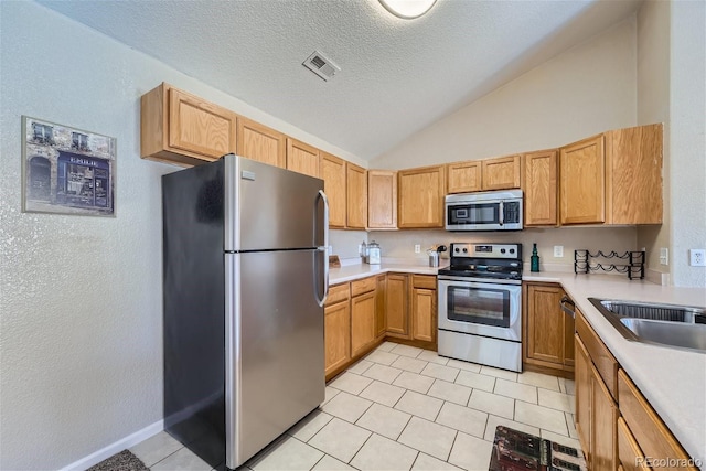 18084 Becket Dr, Parker, CO 80134 - kitchen featuring stainless steel appliances, lofted ceiling, light countertops, light tile patterned flooring, and a textured ceiling