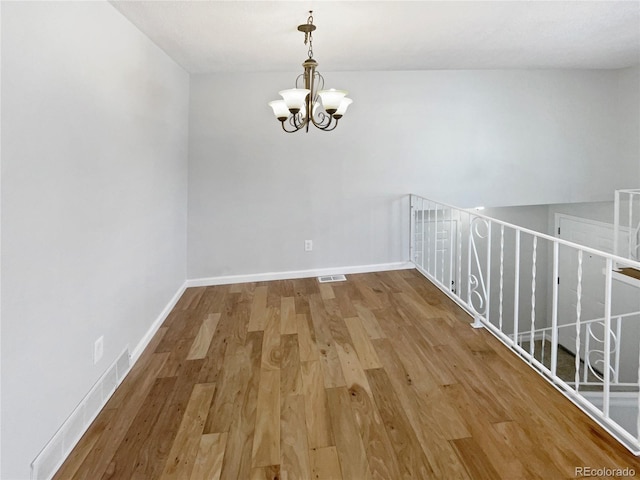 unfurnished room featuring a chandelier and hardwood / wood-style flooring