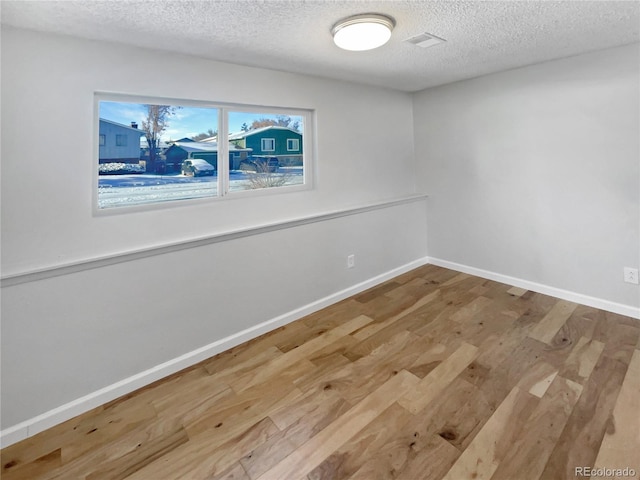 unfurnished room featuring light hardwood / wood-style floors and a textured ceiling