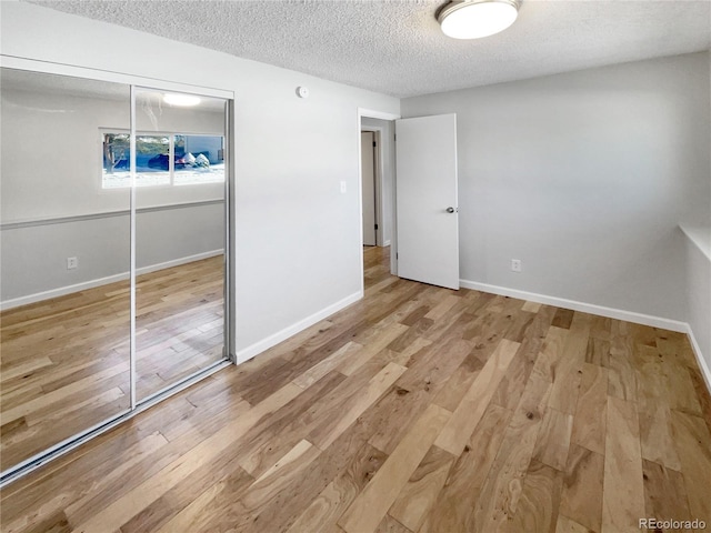 unfurnished bedroom with a textured ceiling, a closet, and light hardwood / wood-style flooring