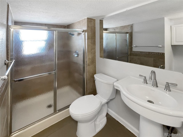 bathroom featuring toilet, a shower with shower door, tile patterned floors, a textured ceiling, and sink