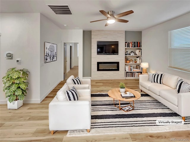 living room with a fireplace, wood finished floors, visible vents, baseboards, and a ceiling fan