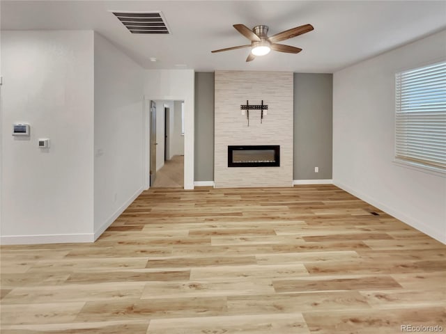 unfurnished living room featuring light wood-style floors, a fireplace, visible vents, and a ceiling fan