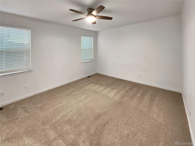 spare room with a ceiling fan, carpet, and baseboards