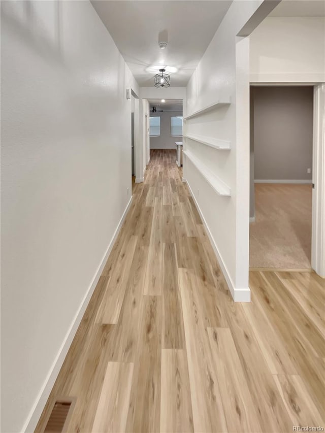 hallway featuring light wood-type flooring and baseboards