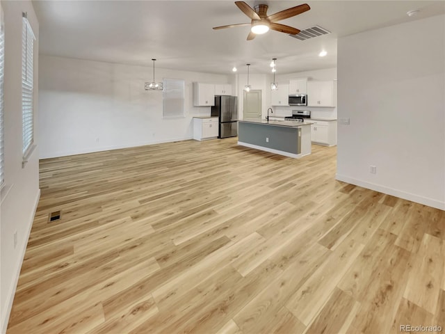 unfurnished living room featuring light wood finished floors, ceiling fan, visible vents, and baseboards