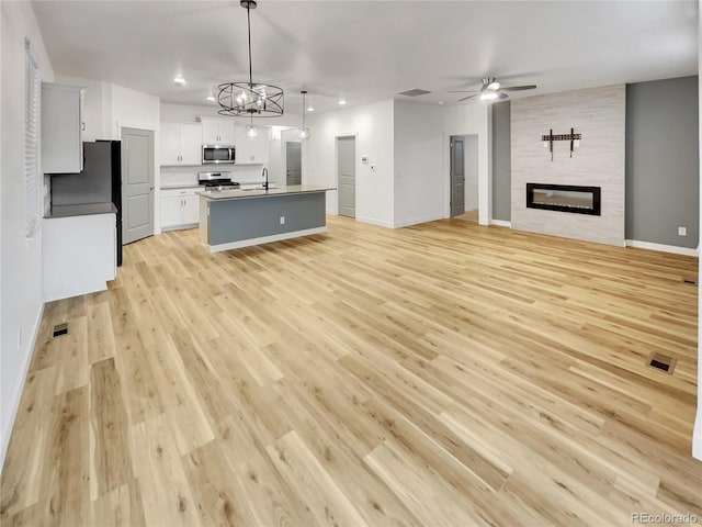 kitchen with stainless steel appliances, open floor plan, a large fireplace, and ceiling fan